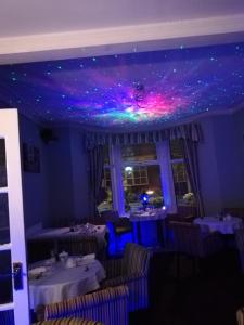 a dining room with purple and green lights on the ceiling at The Glenroy Guest House in Blackpool