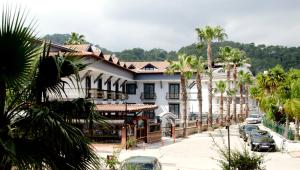 a large white house with palm trees on a street at Orange Garden Apart Hotel in Kemer