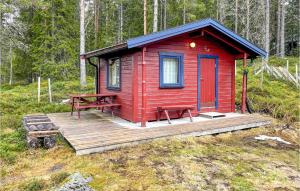 une cabine rouge avec une terrasse en bois dans les bois dans l'établissement 4 Bedroom Beautiful Home In Snertingdal, 