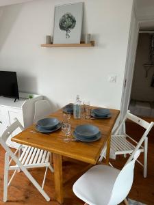 una mesa de madera con sillas, platos y vasos. en Superbe appartement proche centre ville, thermes en Bagnères-de-Bigorre