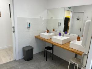 łazienka z 2 umywalkami i dużym lustrem w obiekcie Albergue SCQ w Santiago de Compostela