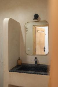 La salle de bains est pourvue d'un lavabo et d'un miroir. dans l'établissement Surf and Friends, à Tamraght Ou Fella