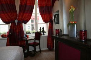 a bedroom with red curtains and a table and a bed at B&B Con Ampère in Bruges
