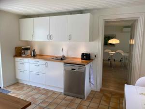 uma cozinha com armários brancos e uma bancada em Idyllically Located Wooden House By The Forest, 2 em Viborg