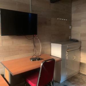 a desk with a computer and a television on a wall at HPLagos BT in Lagos