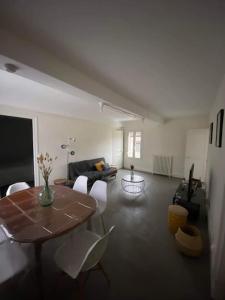 a living room with a table and white chairs at Le gîte de la vieille poste in Envermeu
