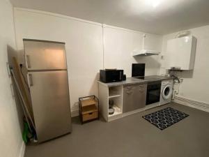 a small kitchen with a refrigerator and a microwave at Le gîte de la vieille poste in Envermeu