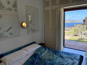Un dormitorio con una cama y una ventana grande. en SAN TEODORO PUNTA EST MONOLOCALE VISTA MARE, en Capo Coda Cavallo