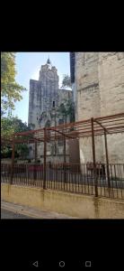 einen Zaun vor einem Gebäude mit einem Uhrturm in der Unterkunft Studio Centre ville les halles in Avignon