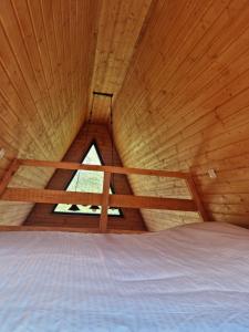a bed in a wooden room with a window at Cottage Tvishi in Tvishi