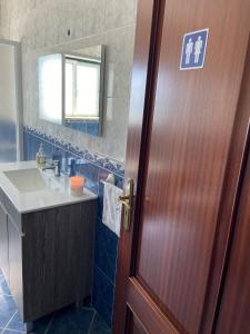 ein Badezimmer mit einer Holztür und einem Waschbecken in der Unterkunft MaJô Alojamento Local in Tábua