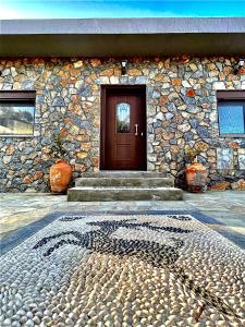 a stone building with a brown door and stairs at Aithonas Villa in Archangelos