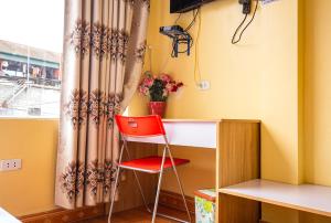 a red chair sitting next to a desk with a window at Nhà Nghỉ Thu Nụ in Mèo Vạc