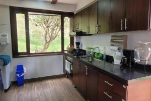 eine Küche mit einer Theke, einem Waschbecken und einem Fenster in der Unterkunft La Rosaleda 3 - Hermosa finca en Paipa in Paipa
