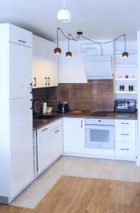 een witte keuken met witte apparatuur en houten vloeren bij Studio dla Dwojga in Sanok
