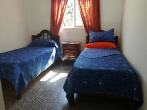 a bedroom with two beds with blue covers and a window at Las Acacias Apart in San Miguel de Tucumán