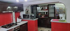 a kitchen with red and black cabinets and a microwave at Casa Diana Govora in Prăjila