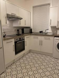 愛丁堡的住宿－The Grove，厨房配有白色橱柜和瓷砖地板。