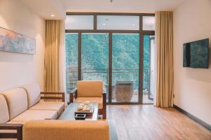 a living room with a couch and a large window at Zhangjiajie National Park Nvue Resorts in Zhangjiajie