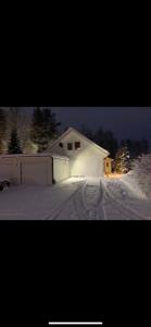 a white house with a garage in the snow at Comfy Cozy Room in beautiful home in Luleå