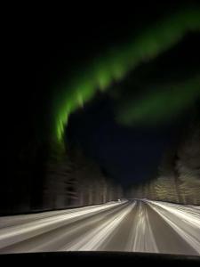 an image of a snowy road with the northern lights at Comfy Cozy Room in beautiful home in Luleå