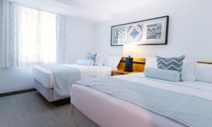 a hotel room with two beds and a couch at Mahalo Diamond Beach Resort in Wildwood Crest