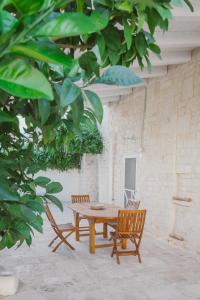 einen Holztisch, 2 Stühle, einen Tisch und Bäume in der Unterkunft Trulli Harmonia con piscina - Alberobello in Alberobello