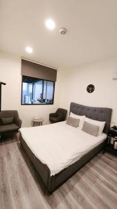 a bedroom with a large white bed and a chair at Stay if you wish Homestay in Jiufen