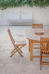 einen Holztisch und Stühle mit einem Tisch und einer Bank in der Unterkunft Trulli Harmonia con piscina - Alberobello in Alberobello