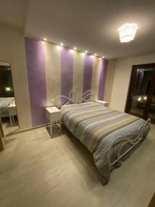 a bedroom with a bed and a purple wall at Appartamento al mare - Porto Recanati in Porto Recanati
