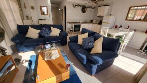 a living room with two blue couches and a kitchen at Casa Mina in Puerto de Santiago