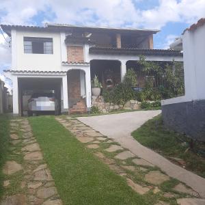 uma casa branca com uma garagem e uma entrada em Casa para Aluguel de Temporada - Carrancas MG em Carrancas