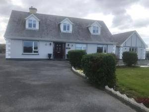 een wit huis met een oprit ervoor bij Riverside in Doonbeg