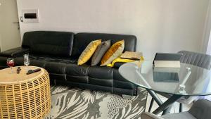 a living room with a black couch and a glass table at CALDESMO - Upmarket Apartment in Pretoria