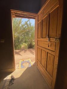 an open door to a room with a view of the desert at Auberge la Palmeraie in Mhamid
