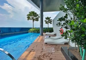 an infinity pool with chaise lounge chairs and palm trees at Amazing KLCC SKY view infinity pool Eaton Residences Suites in Kuala Lumpur