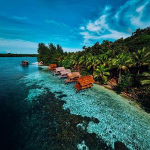 Meos Ambower Homestay Raja Ampat في Fam: جزيرة فيها مجموعة طاولات في الماء