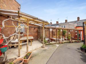 a patio with a wooden pergola with benches and tables at Angeliki - Uk43588 in Ellesmere