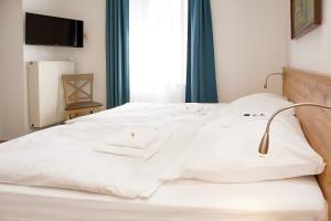 Una cama con sábanas blancas y una lámpara. en Keller Höhe, en Andernach