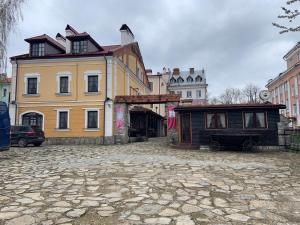 a house and a building on a cobblestone street at Hetman Hotel in Kamianets-Podilskyi