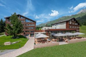 a building with tables and umbrellas in front of it at Valbella Resort in Lenzerheide