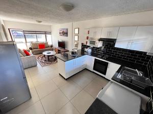 uma cozinha com armários brancos e uma sala de estar em Safi Classic 3 bedroom Apartment 4 em East London