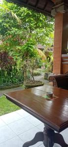 a wooden table sitting in front of a garden at Family Guest House in Ubud