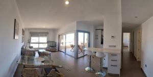 uma cozinha e sala de estar com um sofá e uma mesa em Acogedor apartamento con piscina em Águilas