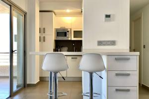 una cocina con 2 sillas blancas y una barra en Acogedor apartamento con piscina, en Águilas