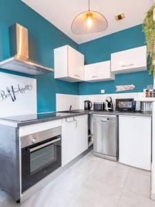una cocina con armarios blancos y una pared azul en Le louisiane/parking/wifi, jardins de la fontaine en Nimes