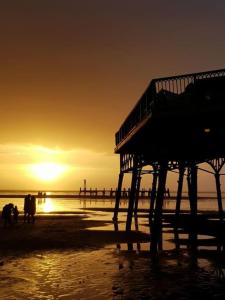 um cais numa praia com o pôr-do-sol ao fundo em Lytham Luxury em Saint Annes on the Sea