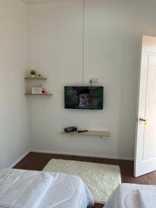 a bedroom with a tv on a white wall at A’Casa Cottage in Kuala Terengganu
