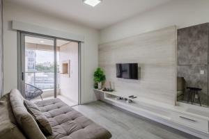 a living room with a couch and a tv on a wall at Trend NCG - Apartament 1602 in Porto Alegre