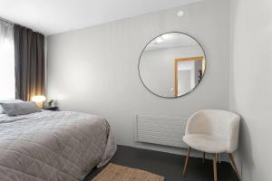 a bedroom with a bed and a mirror and a chair at Cheerful 3BR Down Town Newly Renovated in Reykjavík